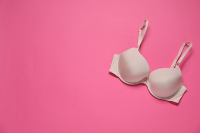 Photo of Beautiful beige bra on pink background, top view. Space for text