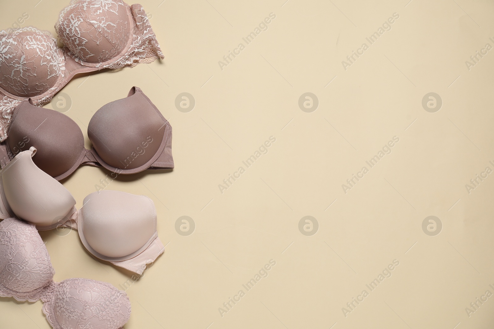 Photo of Beautiful bras on beige background, flat lay. Space for text