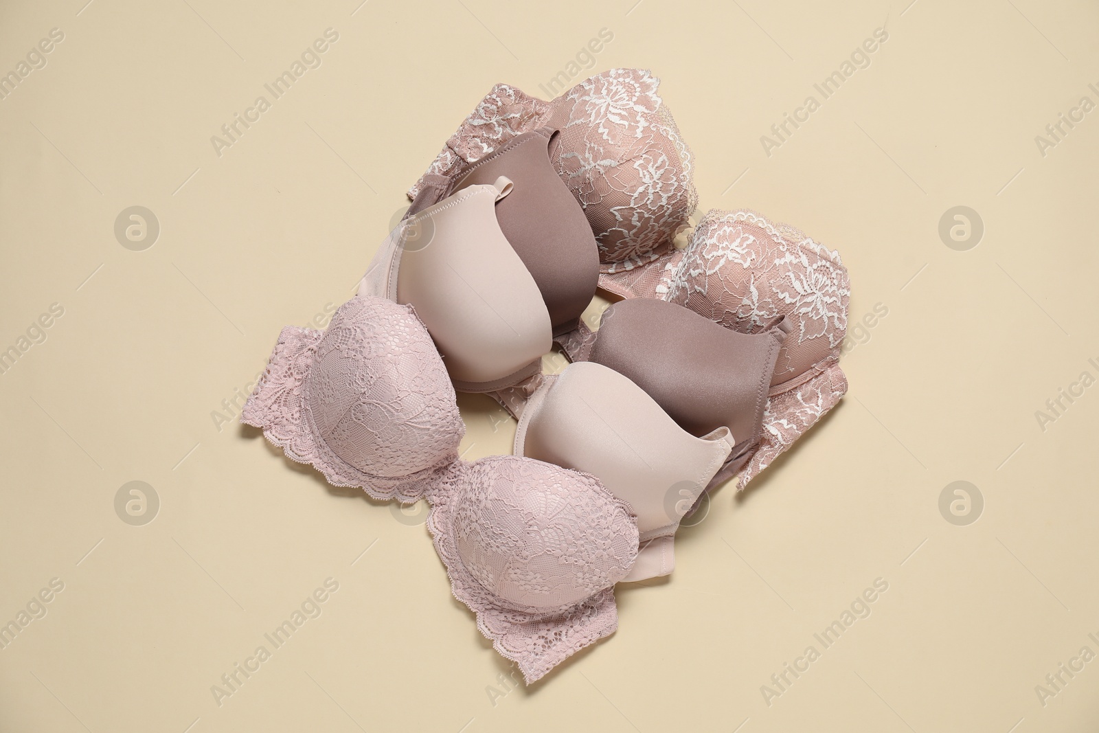 Photo of Beautiful bras on beige background, flat lay