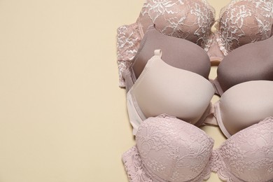 Photo of Beautiful bras on beige background, above view. Space for text