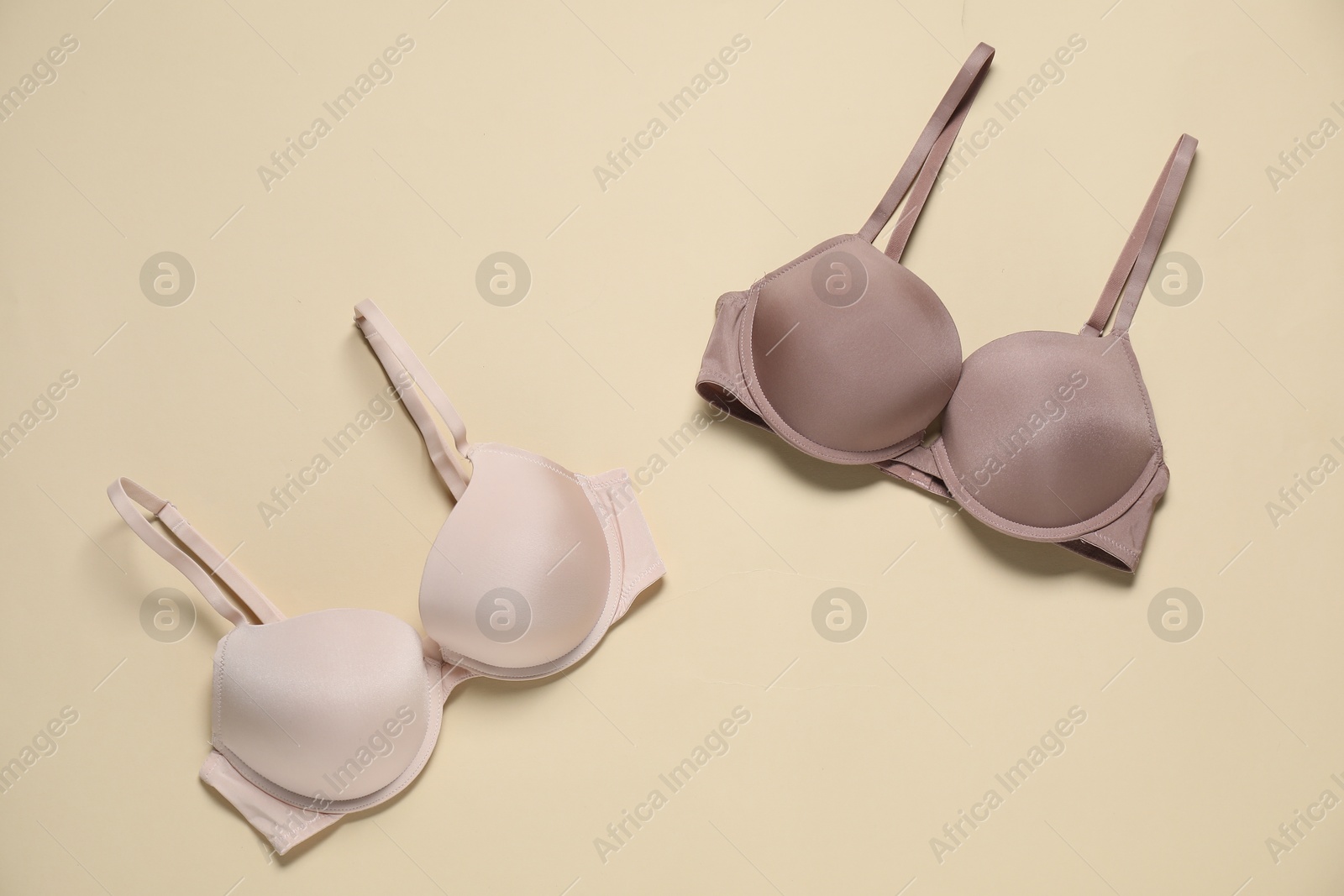 Photo of Beautiful bras on beige background, flat lay