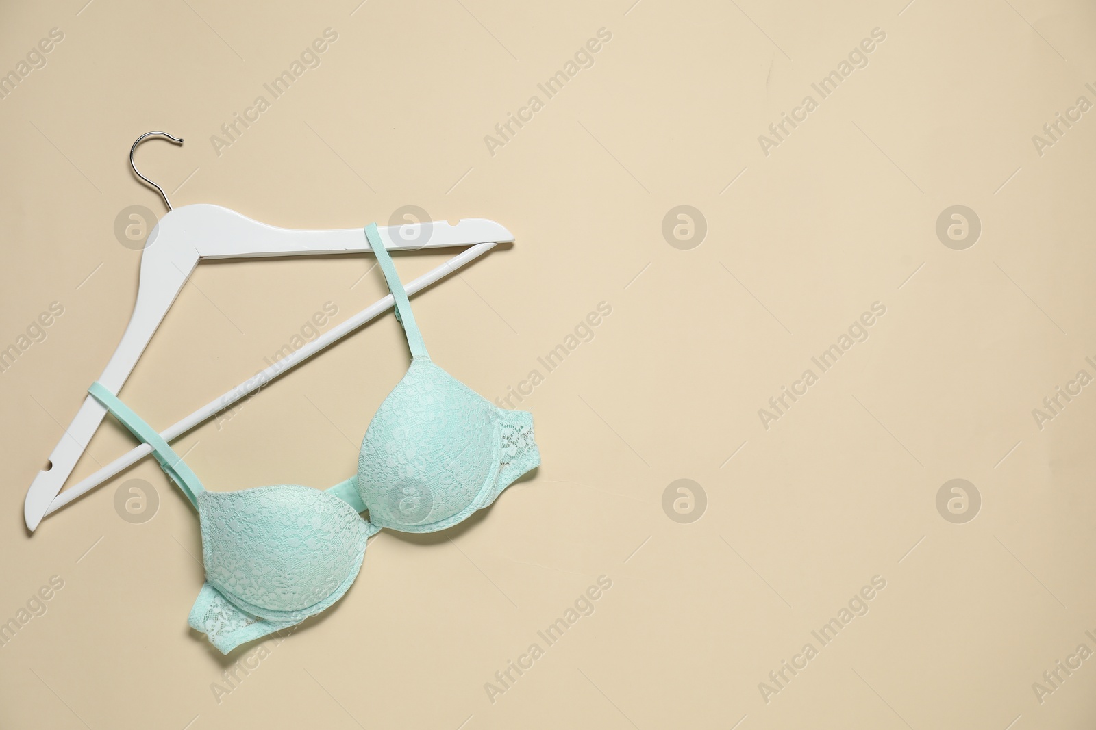 Photo of Hanger with beautiful turquoise bra on beige background, top view. Space for text