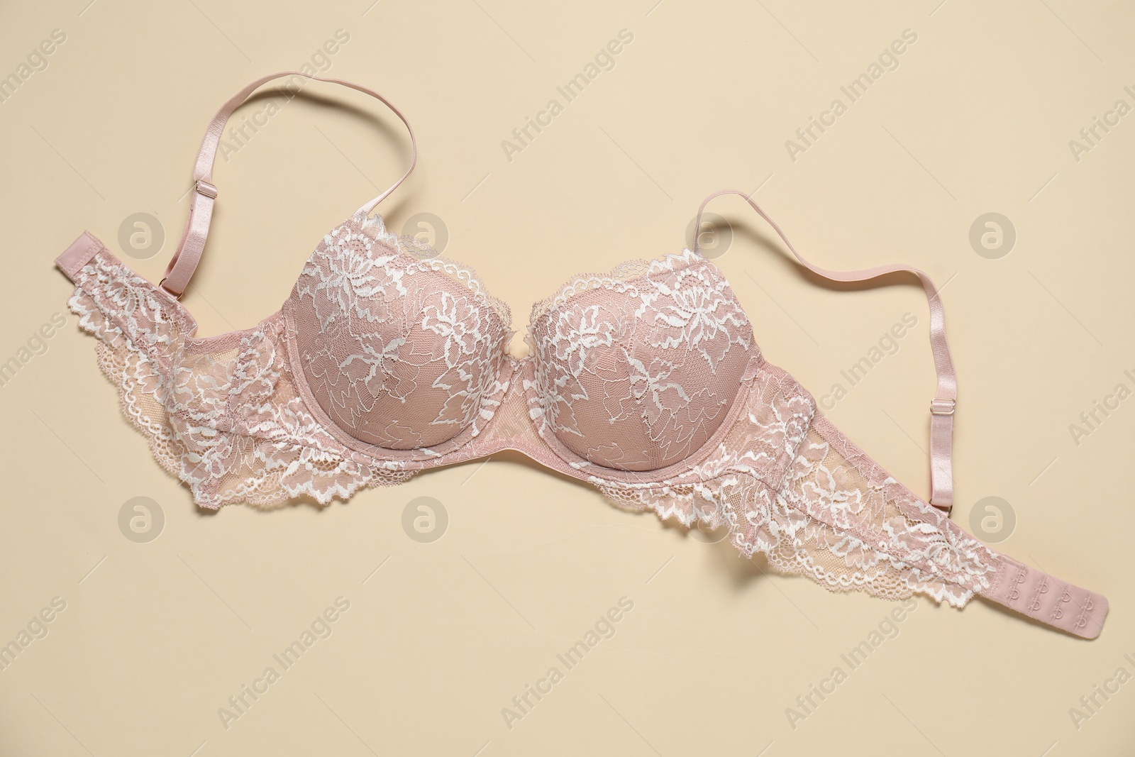 Photo of Beautiful lace bra on beige background, top view