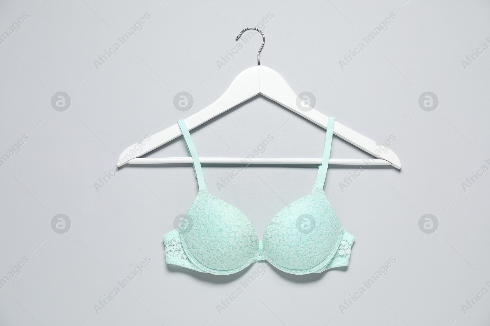 Photo of Hanger with beautiful turquoise bra on light background, top view