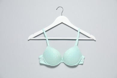 Photo of Hanger with beautiful turquoise bra on light background, top view