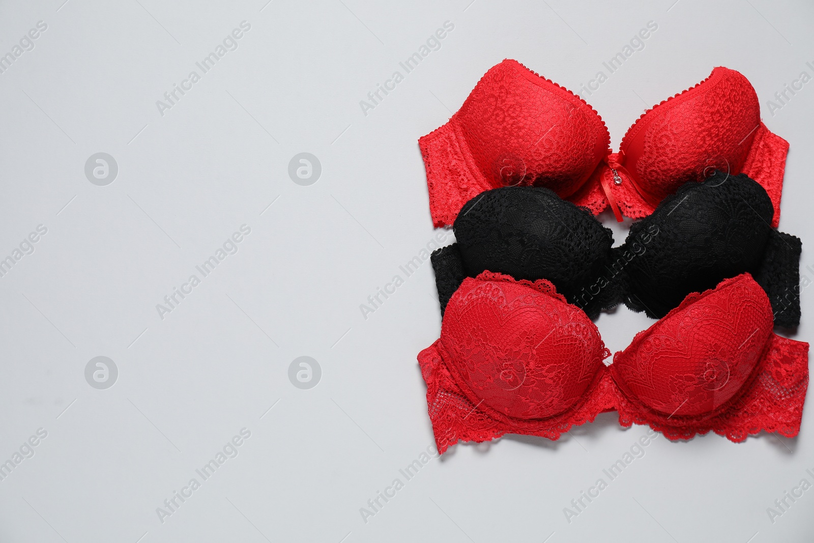 Photo of Beautiful lace bras on light background, flat lay. Space for text