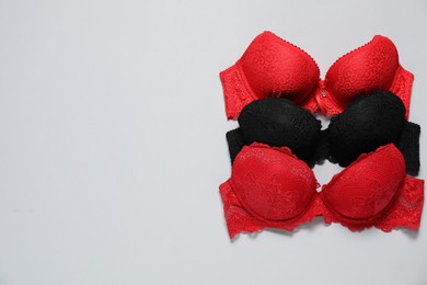 Photo of Beautiful lace bras on light background, flat lay. Space for text