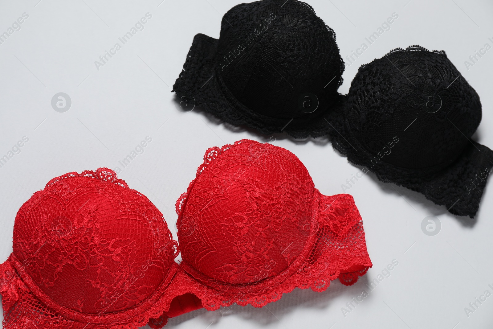 Photo of Beautiful lace bras on light background, above view