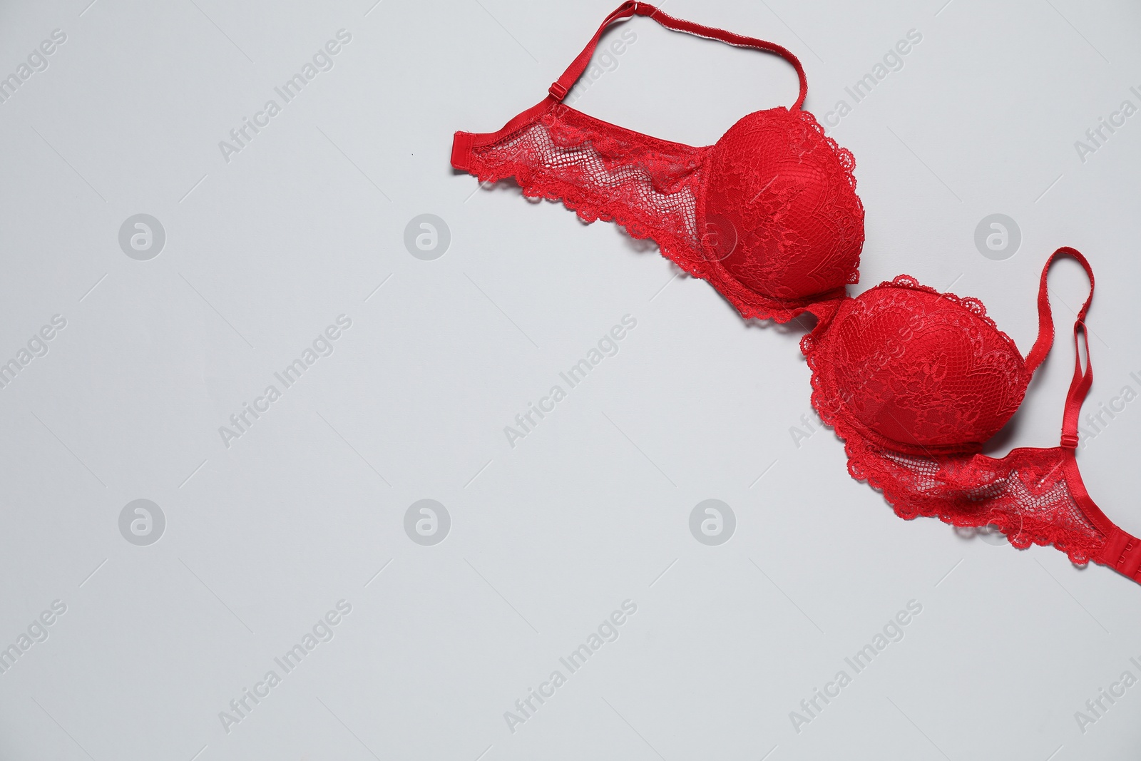 Photo of Beautiful red bra on light background, top view. Space for text