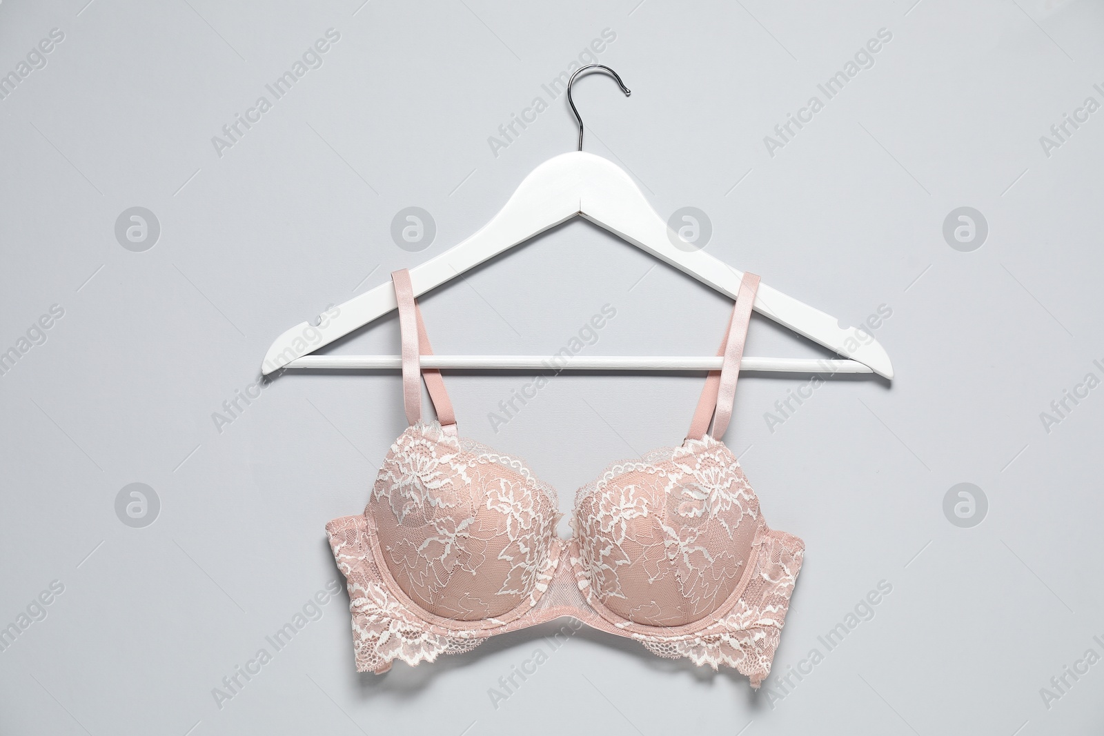 Photo of Hanger with beautiful lace bra on light background, top view