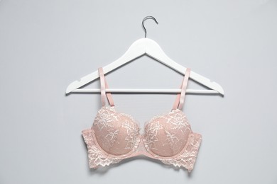 Photo of Hanger with beautiful lace bra on light background, top view