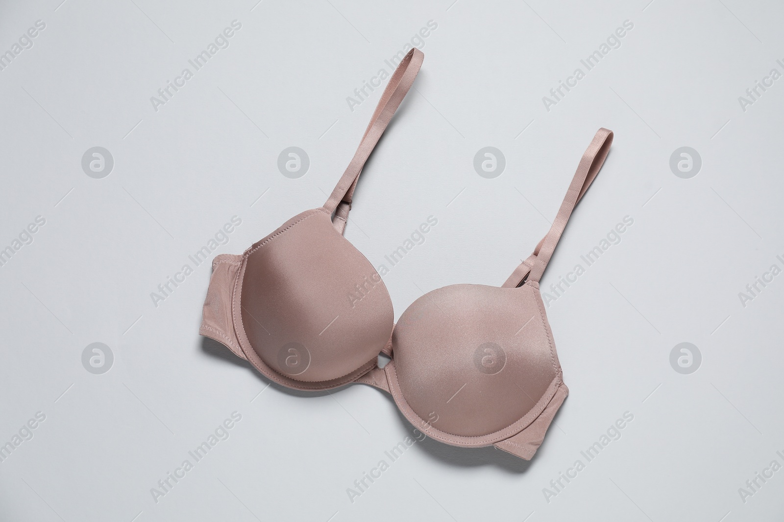 Photo of Beautiful beige bra on light background, top view