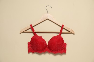 Photo of Hanger with beautiful red bra on beige background, top view