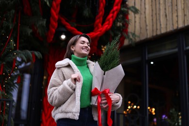 Photo of Happy woman with thuja tree outdoors, low angle view