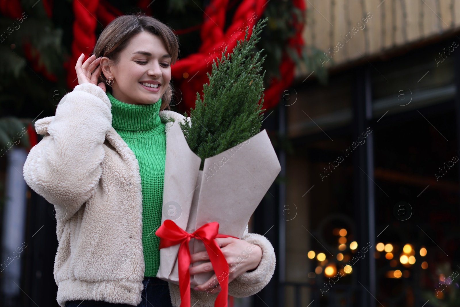 Photo of Happy woman with thuja tree outdoors, space for text