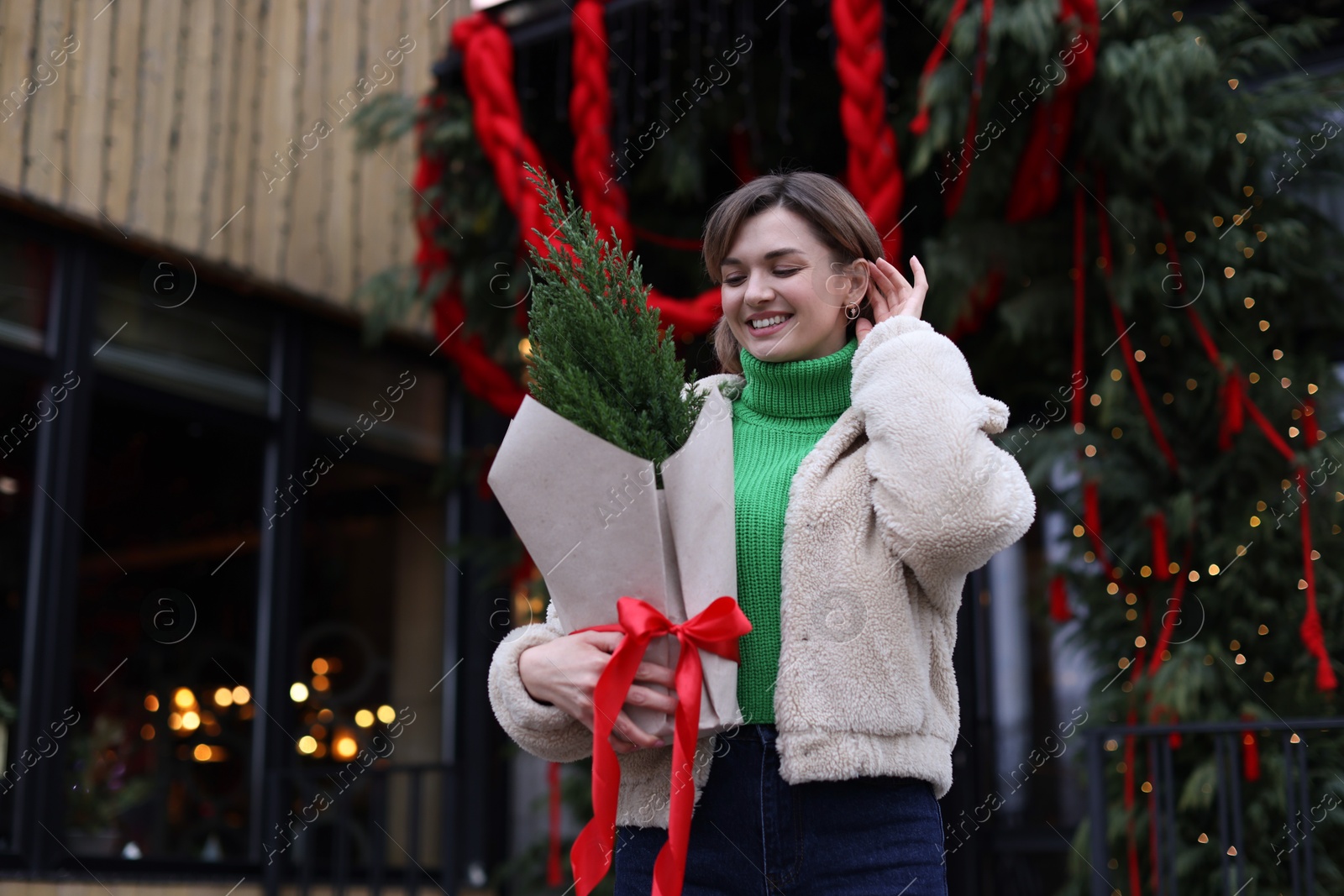 Photo of Happy woman with thuja tree outdoors, space for text