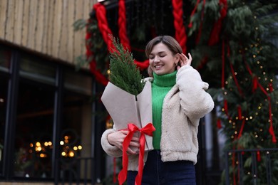 Photo of Happy woman with thuja tree outdoors, space for text