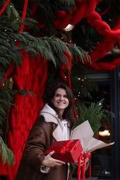 Photo of Happy woman with thuja tree and gift outdoors