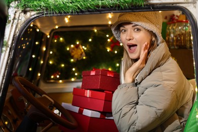 Photo of Excited woman with gifts in bus decorated for Christmas, view from outside