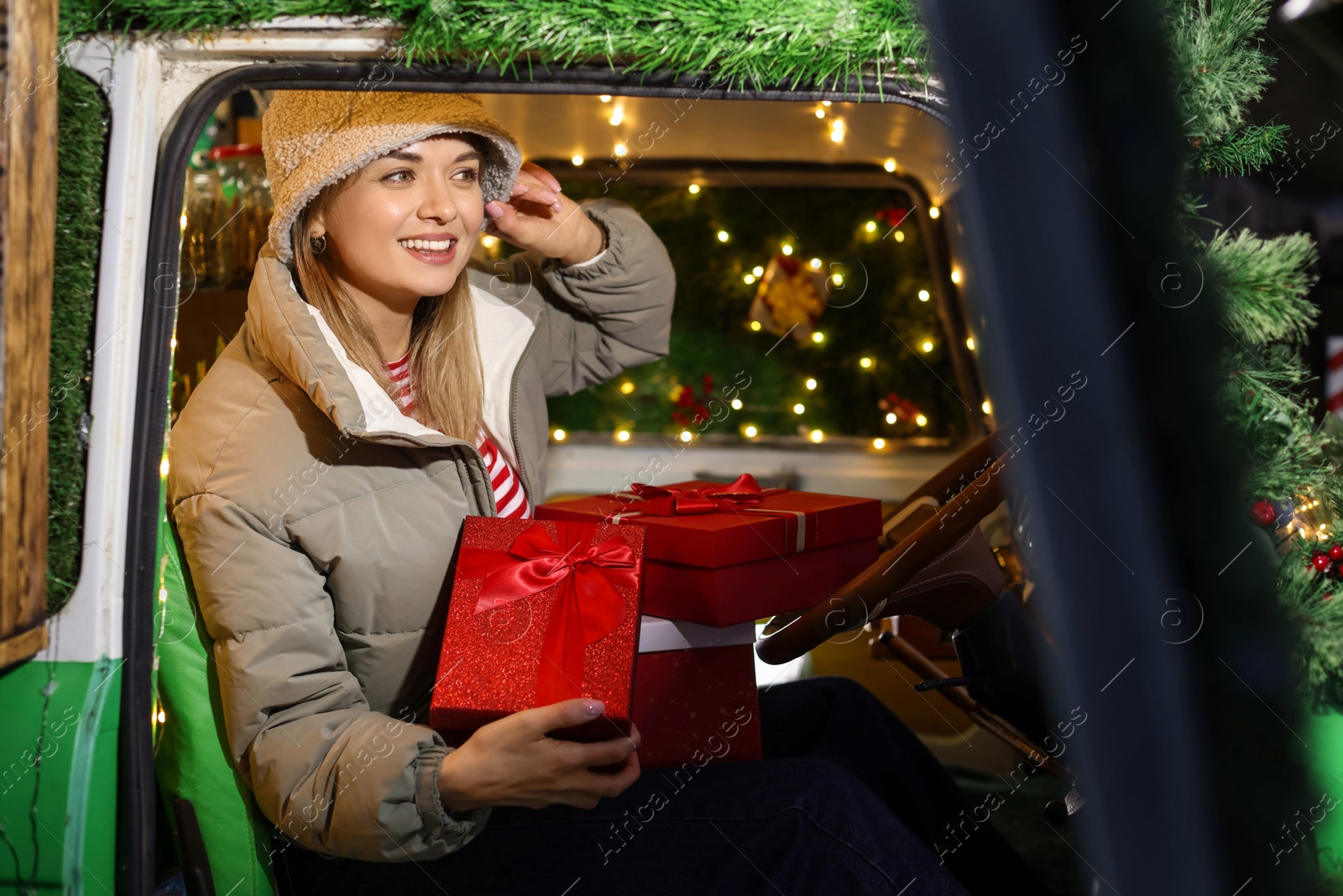 Photo of Happy woman with gifts in bus decorated for Christmas, view from outside