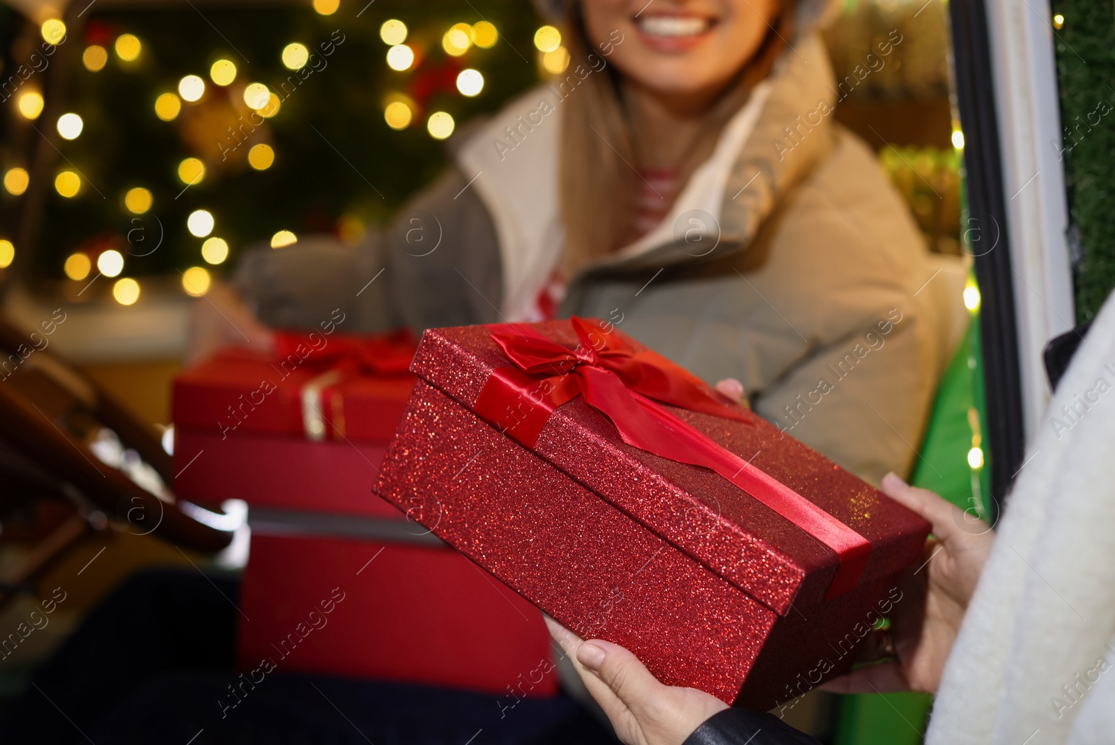 Photo of Woman presenting Christmas gifts to her happy friend, selective focus