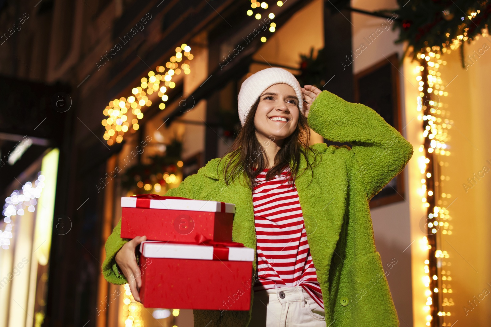 Photo of Happy woman with Christmas gifts outdoors, low angle view