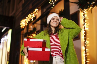 Photo of Happy woman with Christmas gifts outdoors, low angle view