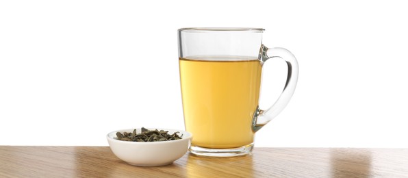 Refreshing green tea in cup and dry leaves on wooden table against white background