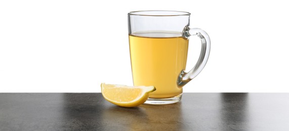 Refreshing green tea in cup and slice of lemon on grey textured table against white background