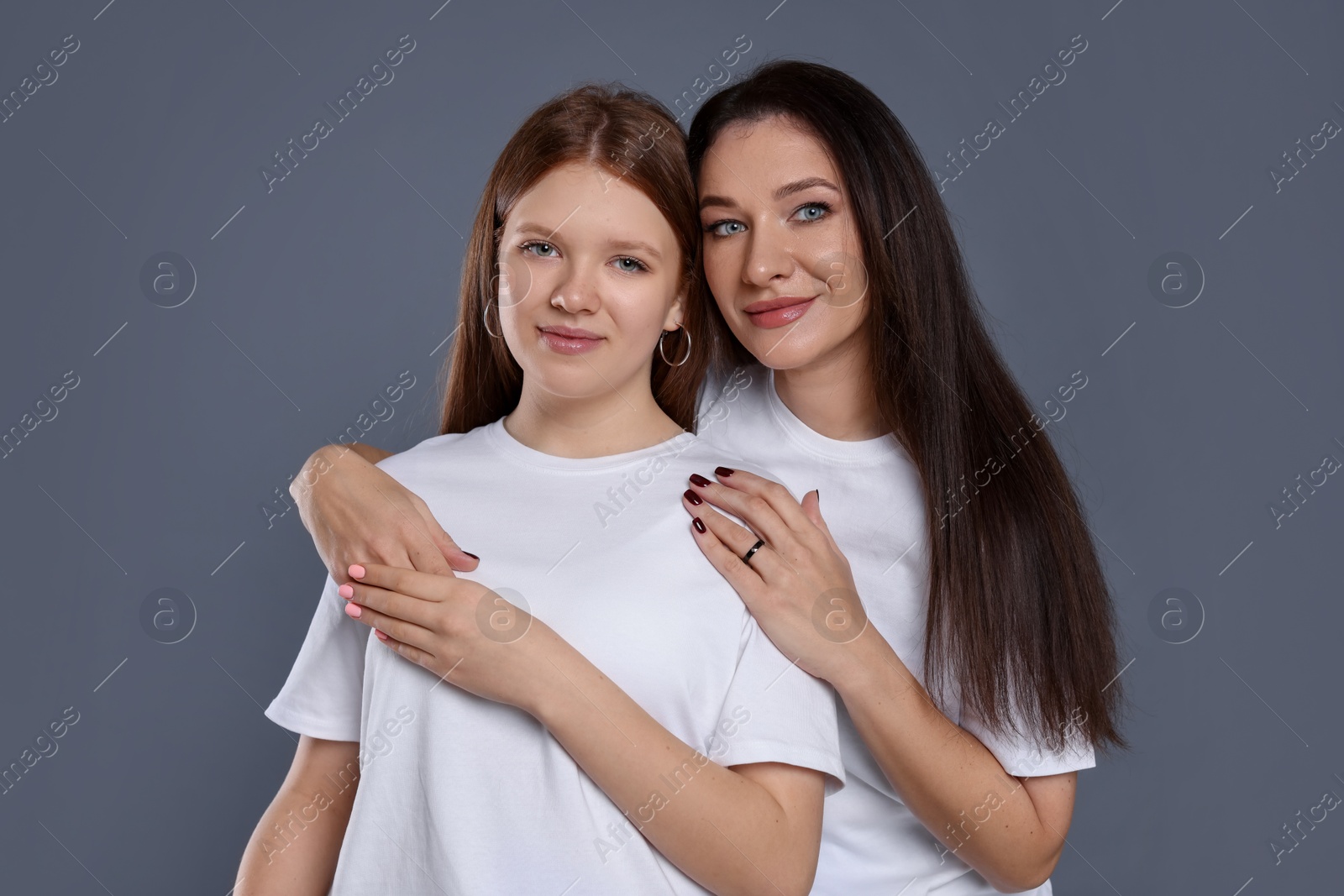 Photo of Portrait of beautiful mother with teenage daughter on grey background