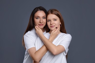 Photo of Portrait of beautiful mother with teenage daughter on grey background