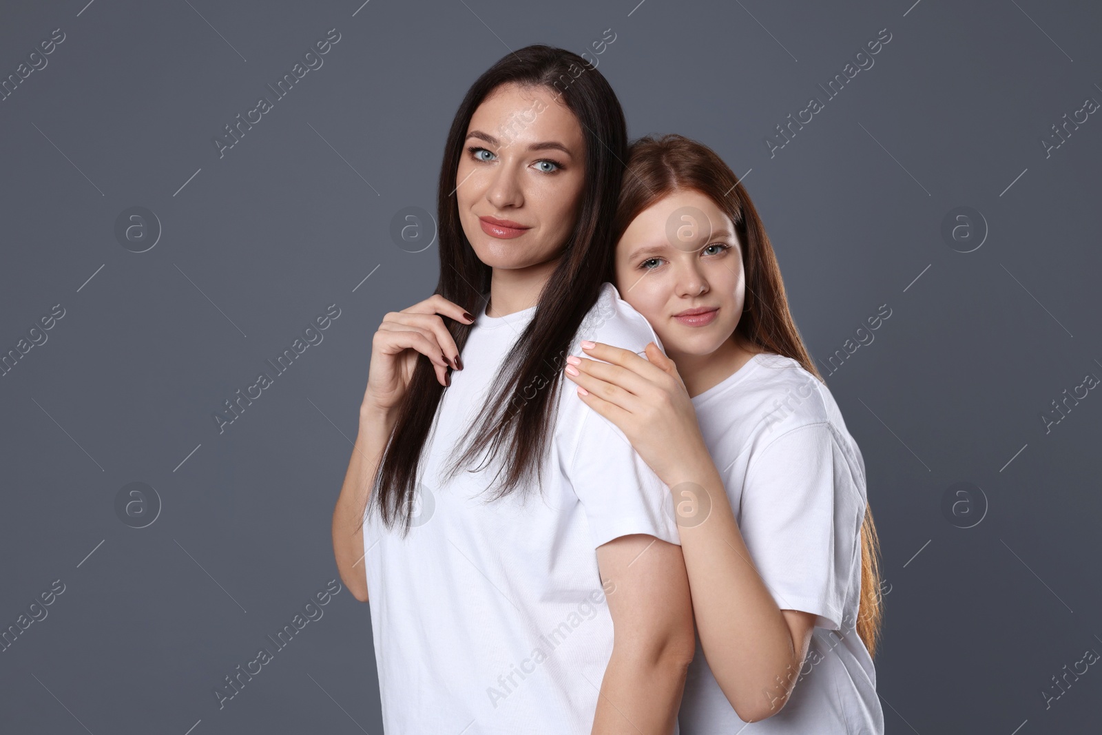 Photo of Portrait of beautiful mother with teenage daughter on grey background