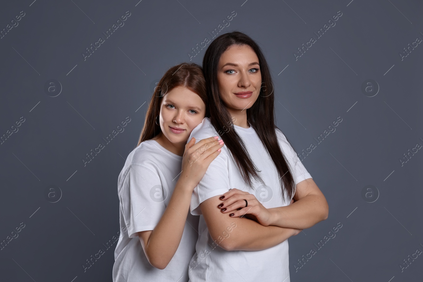 Photo of Portrait of beautiful mother with teenage daughter on grey background