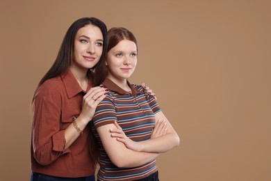 Photo of Portrait of beautiful mother with teenage daughter on dark beige background, space for text