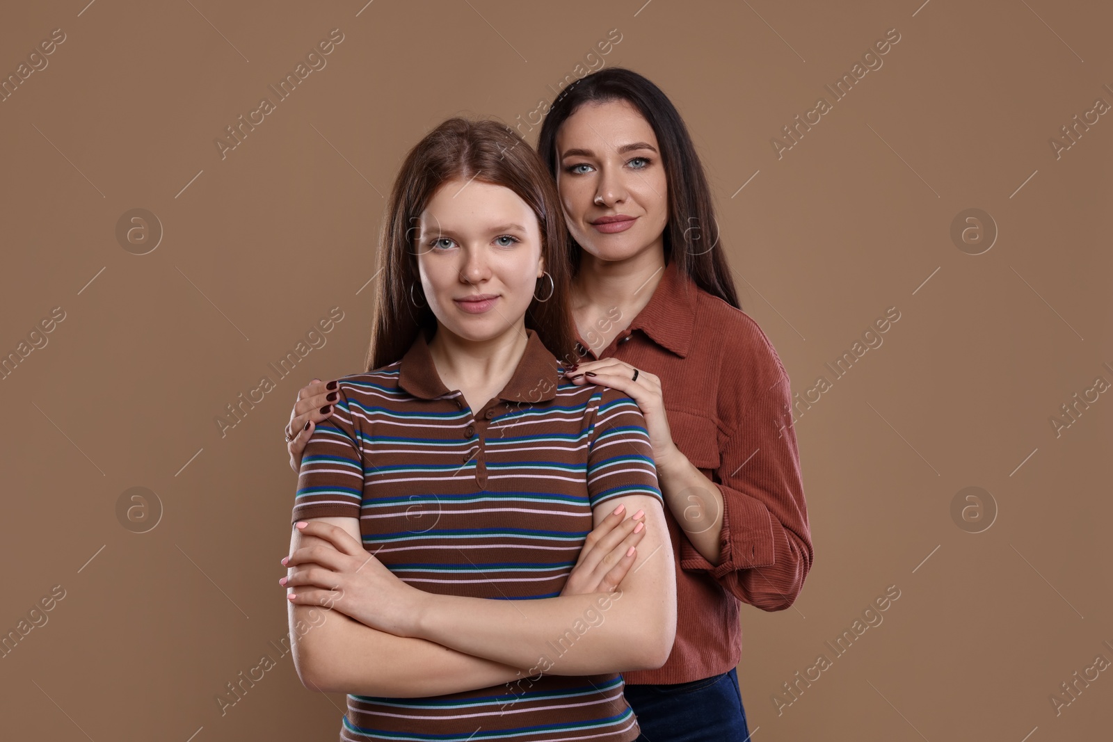 Photo of Portrait of beautiful mother with teenage daughter on dark beige background