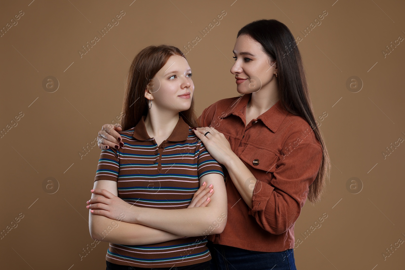 Photo of Portrait of beautiful mother with teenage daughter on dark beige background