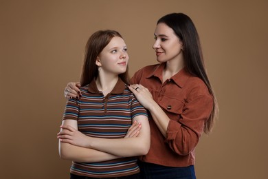 Photo of Portrait of beautiful mother with teenage daughter on dark beige background