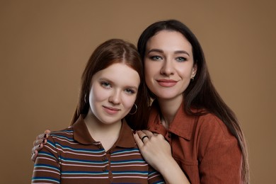 Photo of Portrait of beautiful mother with teenage daughter on dark beige background