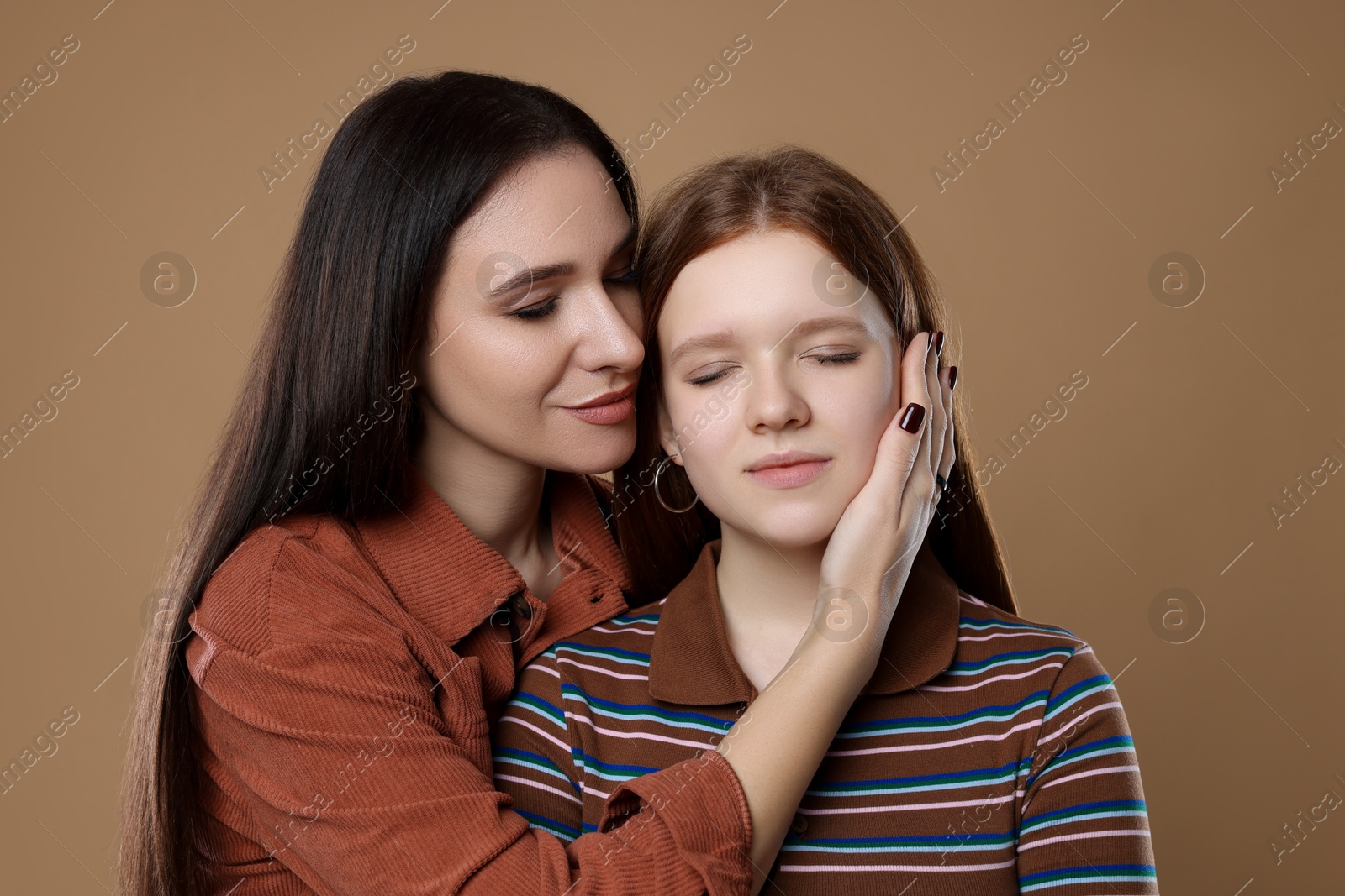 Photo of Portrait of beautiful mother with teenage daughter on dark beige background