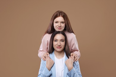 Photo of Portrait of beautiful mother with teenage daughter on dark beige background