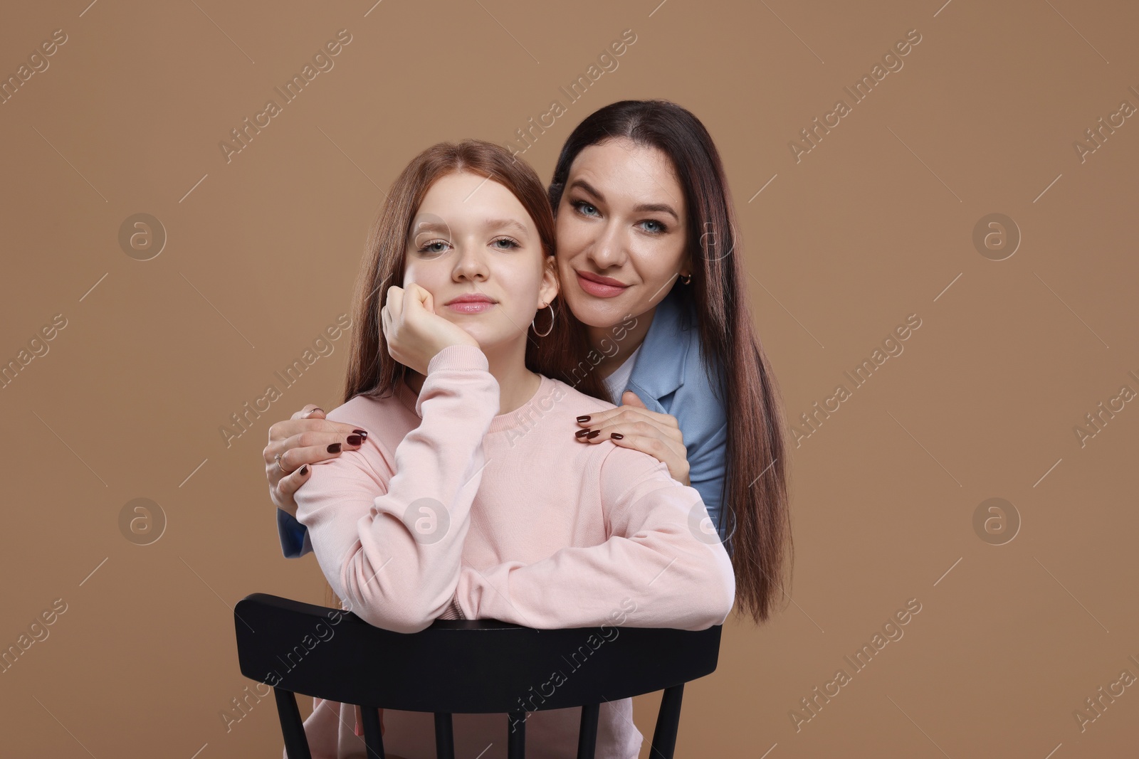 Photo of Portrait of beautiful mother with teenage daughter on dark beige background