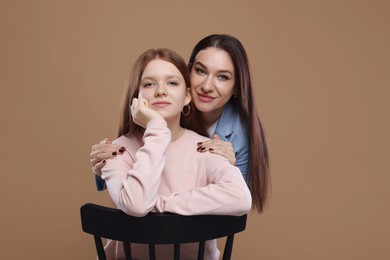 Photo of Portrait of beautiful mother with teenage daughter on dark beige background