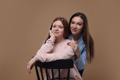 Photo of Portrait of beautiful mother with teenage daughter on dark beige background