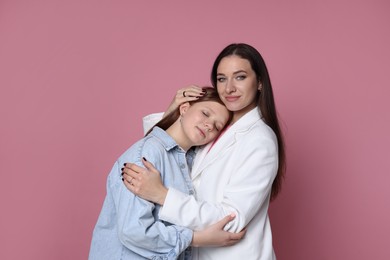 Photo of Family portrait of beautiful mother with teenage daughter on pink background