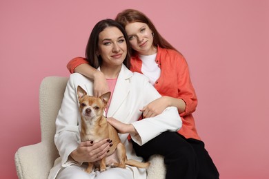 Photo of Portrait of beautiful mother with teenage daughter and cute Chihuahua dog on armchair against pink background