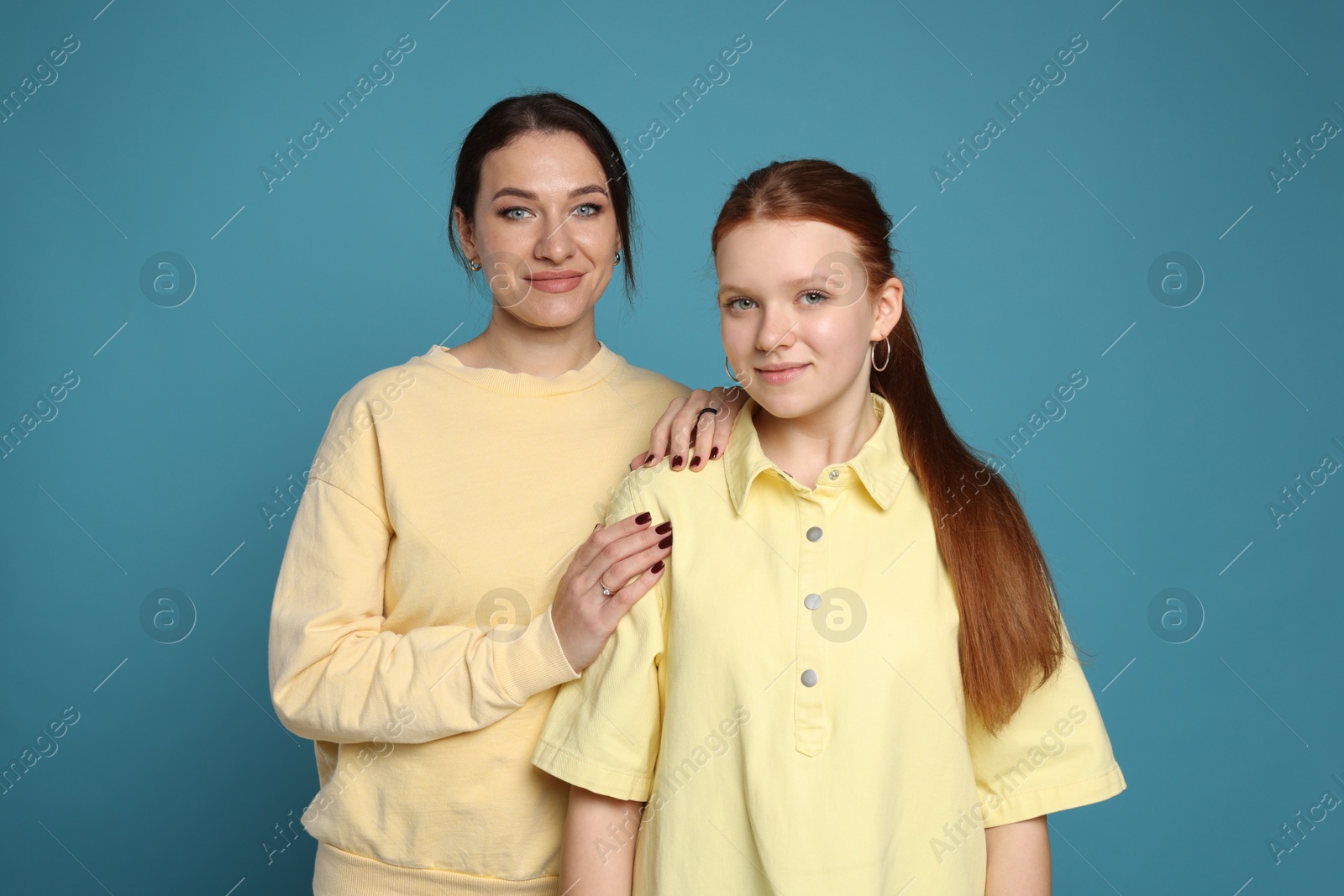 Photo of Portrait of beautiful mother with teenage daughter on light blue background