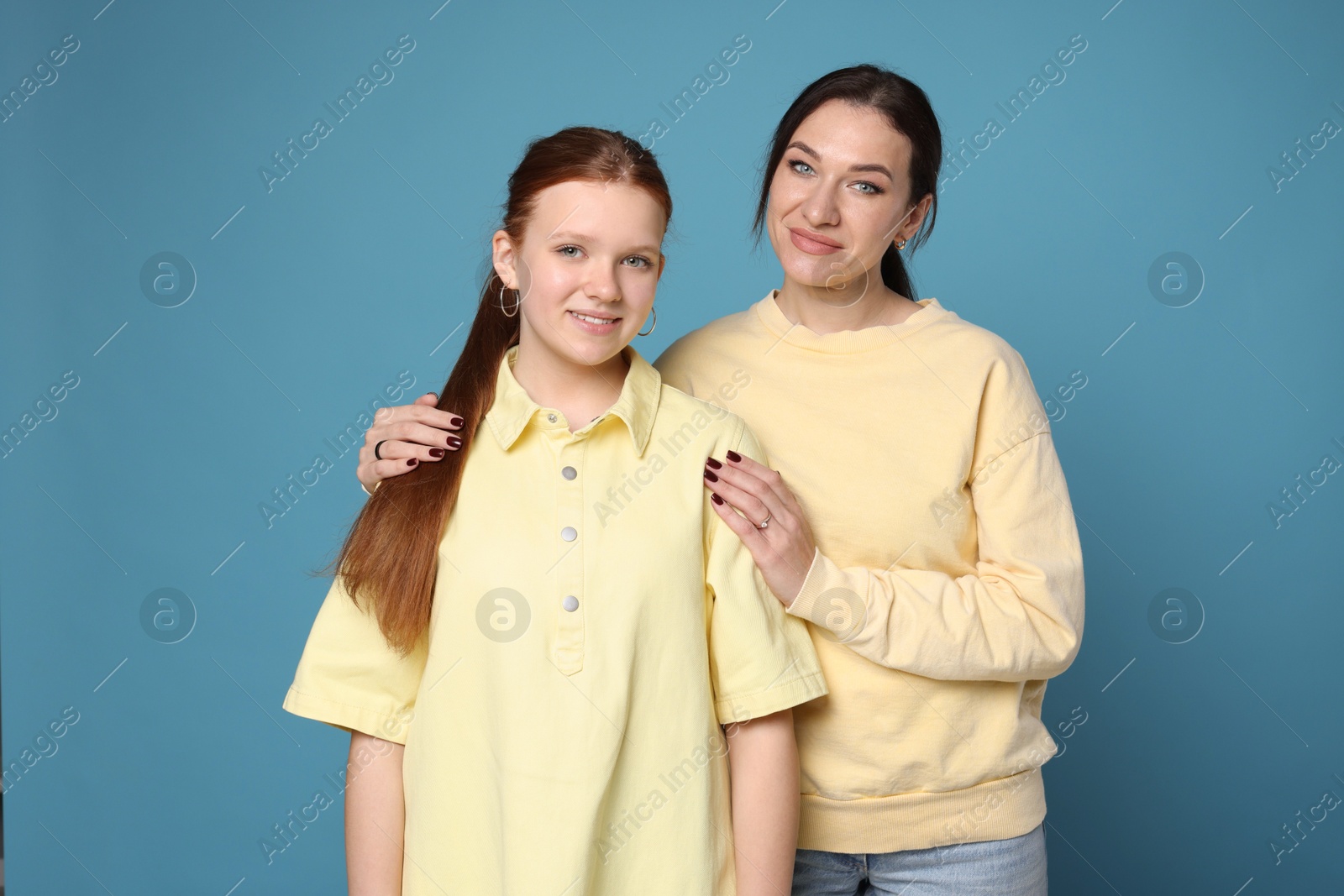 Photo of Portrait of beautiful mother with teenage daughter on light blue background