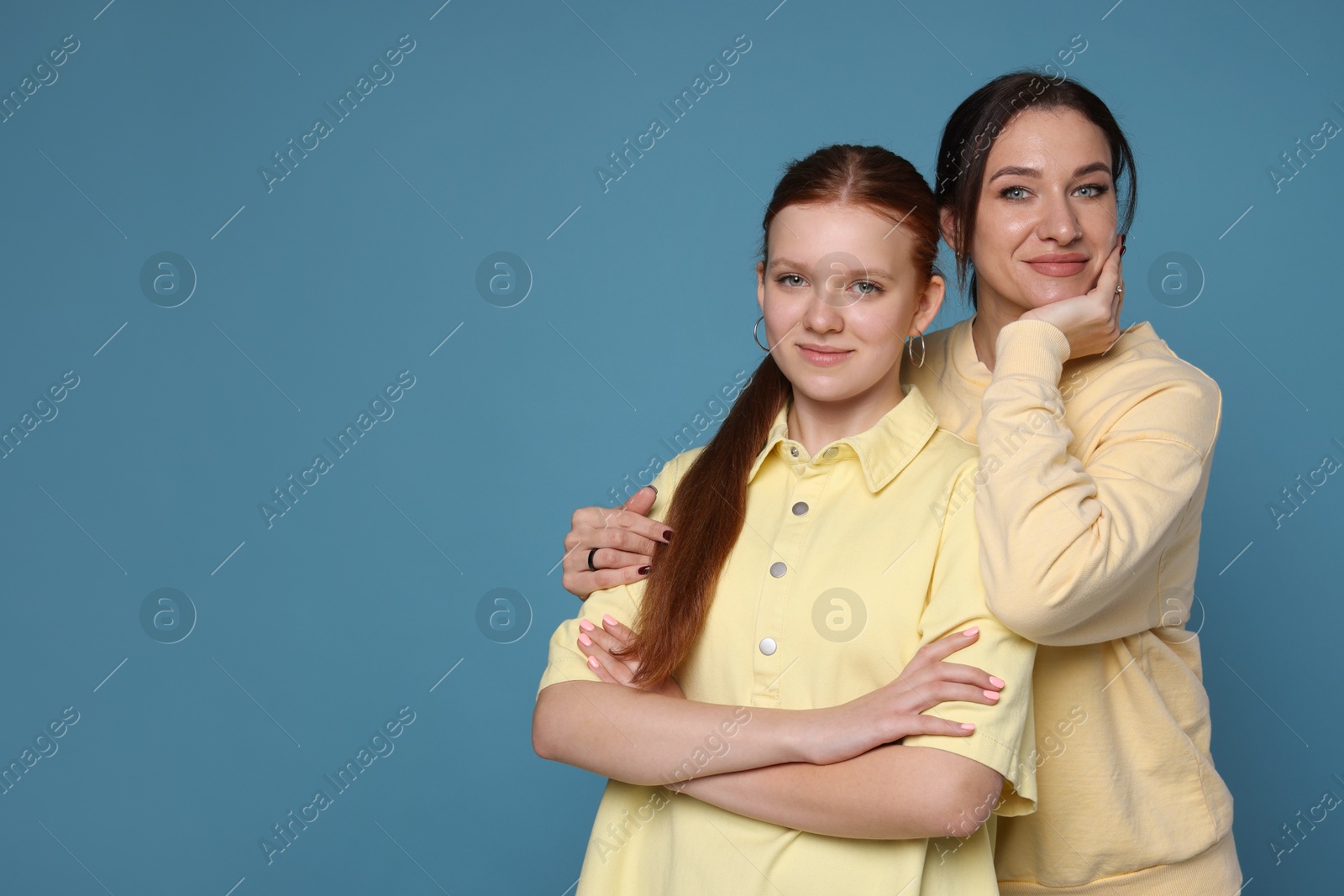 Photo of Portrait of beautiful mother with teenage daughter on light blue background, space for text