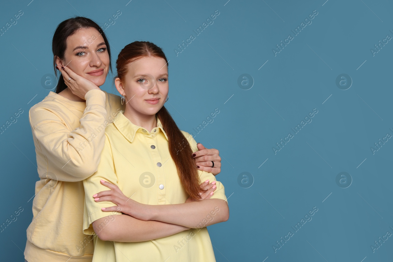 Photo of Portrait of beautiful mother with teenage daughter on light blue background, space for text