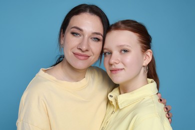 Photo of Portrait of beautiful mother with teenage daughter on light blue background